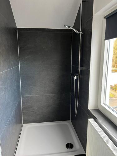 a bathroom with a shower with a black wall at Unique geräumige 2 Zimmerwohnung in Tuttlingen mit Netflix, Sauna und Fitness in Tuttlingen