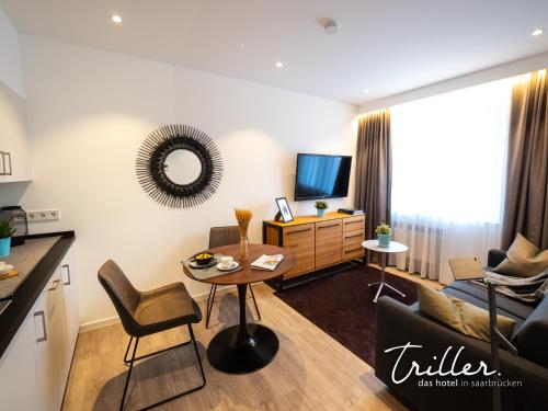 a living room with a couch and a table at Hotel Am Triller - Hotel & Serviced Apartments in Saarbrücken