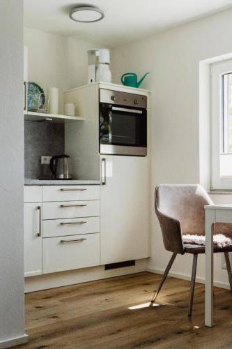 a kitchen with a refrigerator and a table with a chair at Wohnen auf Zeit in Weingarten in Weingarten