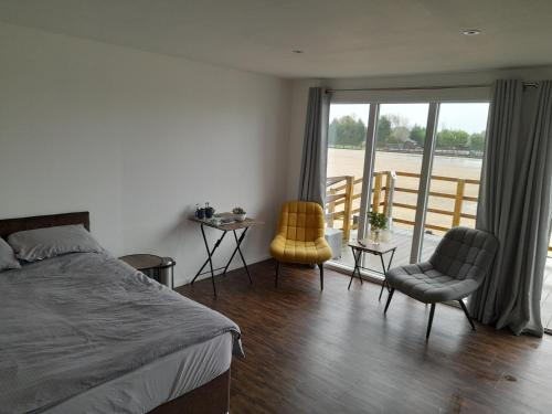 a bedroom with a bed and two chairs and a balcony at Weston Lawns Lodges in Bulkington