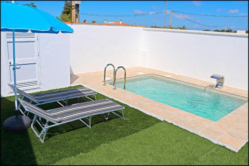 una piscina con una sedia e un ombrellone di Chalet los Morenos a Conil de la Frontera