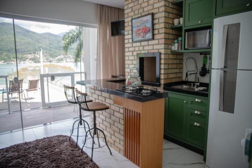 a kitchen with green cabinets and a counter with a stove at Paraíso da Enseada de Brito in Palhoça