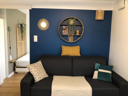 a black couch in a room with a blue wall at T2 - Tram direct Strasbourg Centre Ville en 11 min - PARKING GRATUIT in Schiltigheim