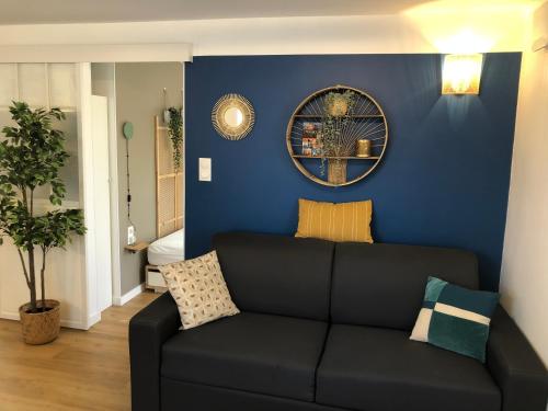 ein Wohnzimmer mit einer schwarzen Couch an einer blauen Wand in der Unterkunft T2 - Tram direct Strasbourg Centre Ville en 11 min - PARKING GRATUIT in Schiltigheim