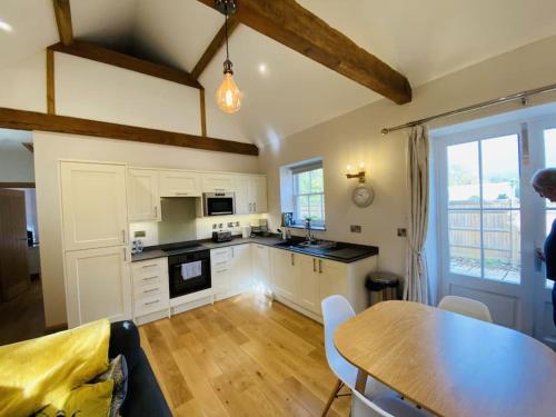 a kitchen with white cabinets and a table and a dining room at The Stable - For A Unique Retreat in Hooe
