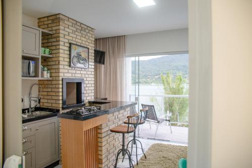 a kitchen with a counter with a stove and a window at Paraíso da Enseada de Brito in Palhoça