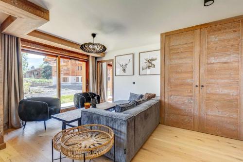 uma sala de estar com um sofá, uma mesa e cadeiras em Sublime appartement 3 chambres avec 200m2 jardin em Megève