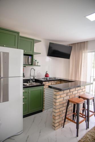 a kitchen with green cabinets and a white refrigerator at Paraíso da Enseada de Brito in Palhoça