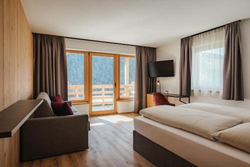 een hotelkamer met een bed en een bank bij Aria de Munt in San Vigilio Di Marebbe