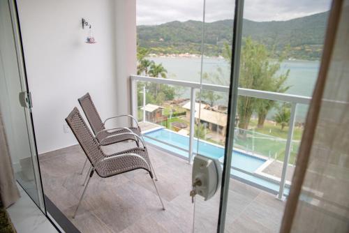 a balcony with two chairs and a swimming pool at Paraíso da Enseada de Brito in Palhoça