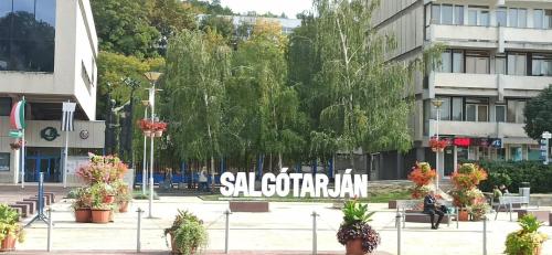 a sign in the middle of a city with plants at Karancs Apartman Salgótarján in Salgótarján