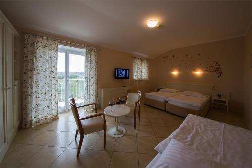 a bedroom with two beds and a table and chairs at Hotel Kozana in Dobrovo