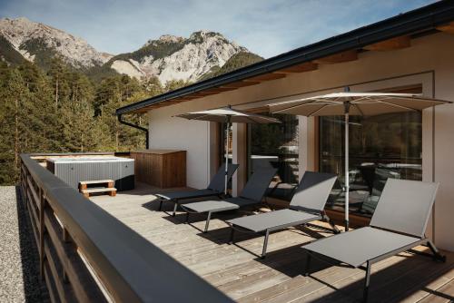 a deck with chairs and umbrellas on a house at Aria de Munt in San Vigilio Di Marebbe
