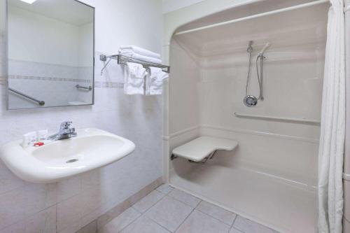 a white bathroom with a sink and a shower at Super 8 by Wyndham Ambassador Bridge Windsor ON in Windsor