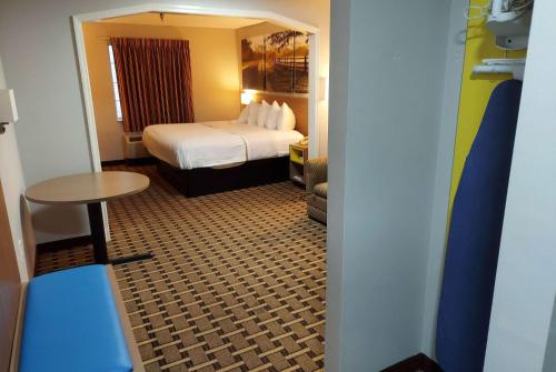 a hotel room with a bed and a table at Days Inn & Suites by Wyndham Huntsville in Huntsville