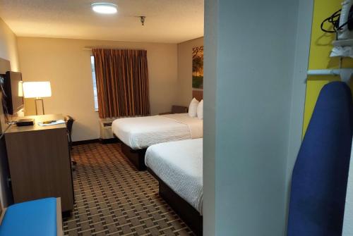 a hotel room with two beds and a television at Days Inn & Suites by Wyndham Huntsville in Huntsville