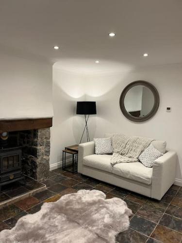 a living room with a white couch and a mirror at Mount Cottage in Conwy