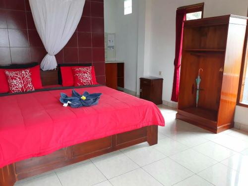 a bedroom with a red bed with a red comforter at One Homestay and Warung in Munduk