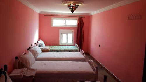 a room with four beds in a room with red walls at Hôtel Restaurant BOUGAFER in Oulad Akkou