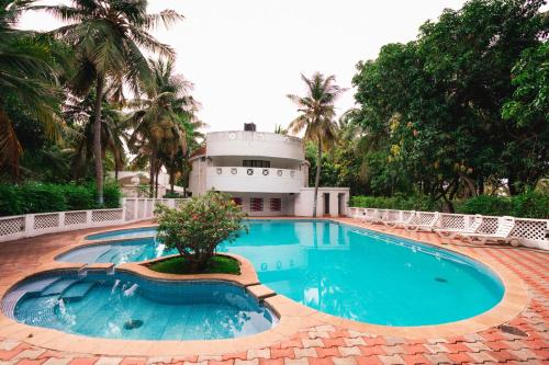a swimming pool with a building in the background at Shelter Beach Resort in Mahabalipuram