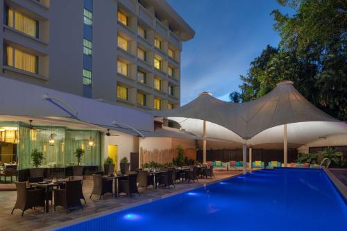 a hotel with a swimming pool and tables and umbrellas at Radisson Hotel Brunei Darussalam in Bandar Seri Begawan