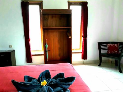 a bedroom with a red bed with a flower on it at One Homestay and Warung in Munduk