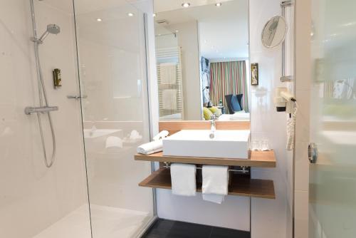 La salle de bains est pourvue d'un lavabo et d'une douche. dans l'établissement Hotel Am Triller - Hotel & Serviced Apartments, à Sarrebruck