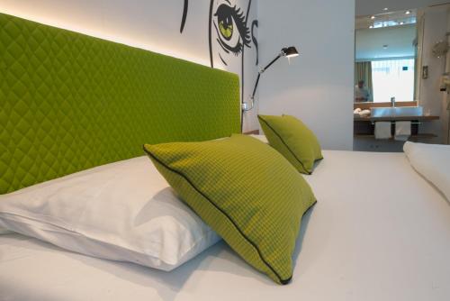 a bed with a green headboard and two pillows at Hotel Am Triller - Hotel & Serviced Apartments in Saarbrücken