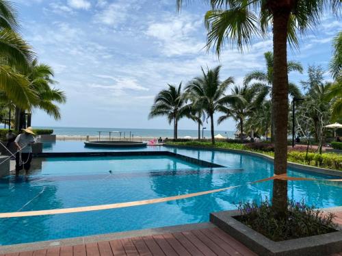 a large swimming pool with palm trees and the ocean at TimurBay Residence 2Bedroom with Seaview 6pax Level10 Kuantan in Kampong Tanjong