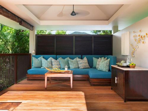 a blue couch on a deck with a table at Raffles Seychelles in Baie Sainte Anne