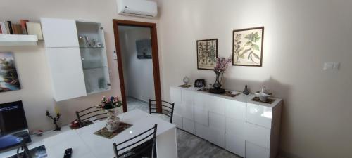 una cocina con armarios blancos y una mesa con flores en Casa a Cocca, en Briatico