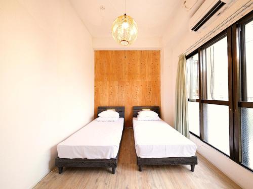 Duas camas num quarto com uma janela em 宮古島 Guesthouse Re-Spect em Ilhas Miyako