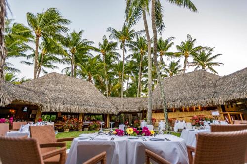 a restaurant with tables and chairs and palm trees at InterContinental Bora Bora Le Moana Resort by IHG in Bora Bora