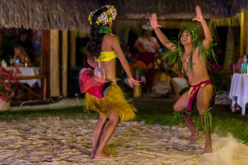 two women in costumes dancing on the beach at InterContinental Bora Bora Le Moana Resort by IHG in Bora Bora