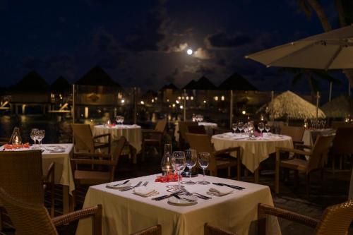 a restaurant with white tables and chairs at night at InterContinental Bora Bora Le Moana Resort by IHG in Bora Bora