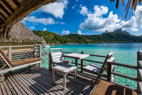 a deck with chairs and a table on the water at InterContinental Bora Bora Le Moana Resort by IHG in Bora Bora