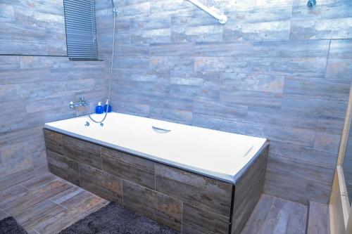 a bath tub in a bathroom with wooden walls at Delux Guesthouse in Volksrust