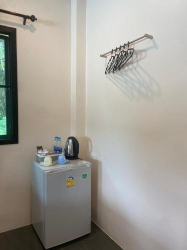 a small white refrigerator in a corner of a room at Hanoii House in Ko Mak