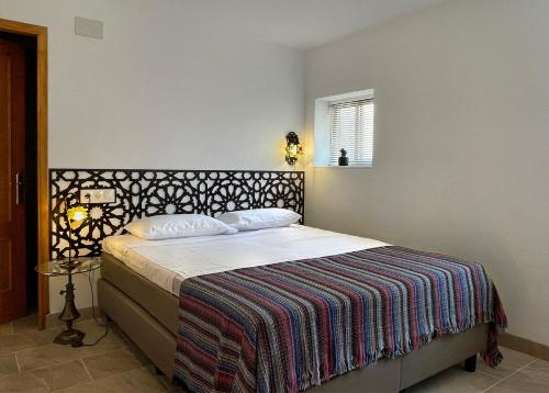 ein Schlafzimmer mit einem Bett mit einer Decke und einem Fenster in der Unterkunft Las Tres Hermanas in Salobreña