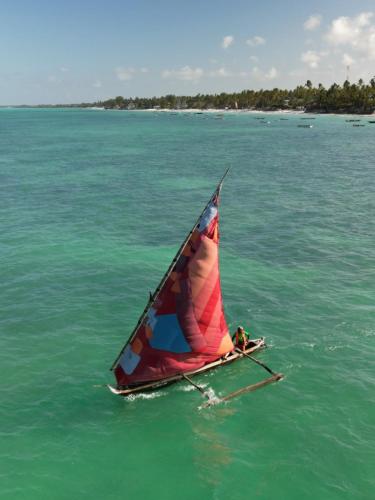 a person on a sail boat in the water at Blue Oyster Hotel in Jambiani
