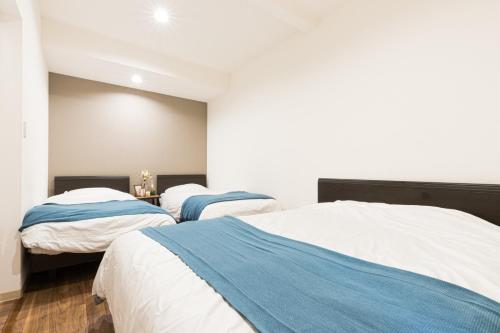 two beds in a room with white and blue at Mita Guest house - Vacation STAY 12100 in Tokyo