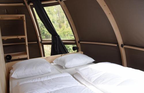 dwa łóżka w pokoju z oknem w obiekcie Panoramatent, in de natuur aan zee w mieście Callantsoog