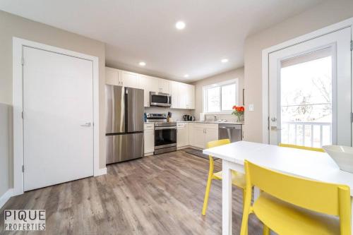 a kitchen with a white table and yellow chairs at NEW, Euro-Style Suite, Whyte Avenue, AC, Netflix, Sleeps 6! in Edmonton