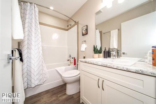 a white bathroom with a toilet and a sink at NEW, Euro-Style Suite, Whyte Avenue, Netflix, Sleeps 6! in Edmonton