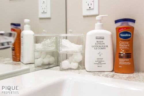 a bathroom counter with a sink with a bottle of lotion at NEW, Euro-Style Suite, Whyte Avenue, AC, Netflix, Sleeps 6! in Edmonton