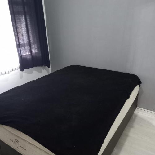 Una cama en una habitación con una manta negra. en Top quarto e sala lindo, en Río de Janeiro