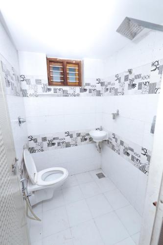 a white bathroom with a toilet and a sink at 7coloursholidays in Kanthalloor