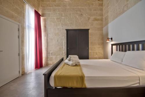 a bedroom with a large bed with a red curtain at Vallettastay Old Lodge Apartment 3 in Valletta