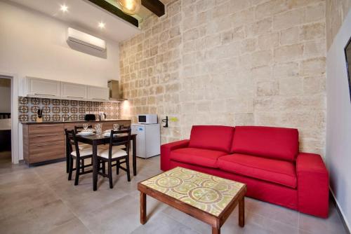 a living room with a red couch and a table at Vallettastay Old Lodge Apartment 3 in Valletta