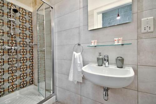 a white bathroom with a sink and a shower at Vallettastay Old Lodge Apartment 3 in Valletta
